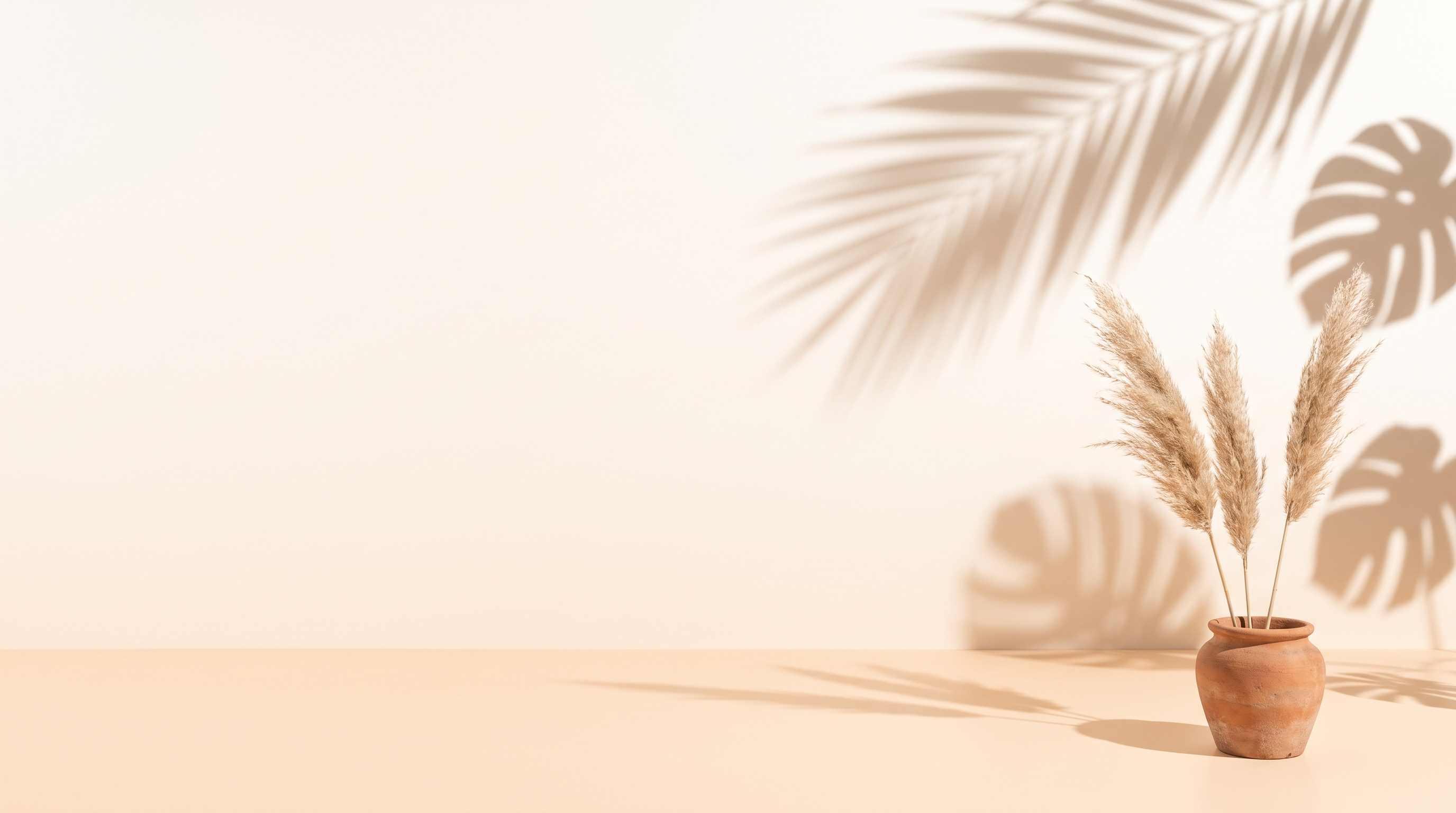 Sunlit cream and peach summer backdrop with palm and monstera leaf shadows and a terracotta pot of pampas grass